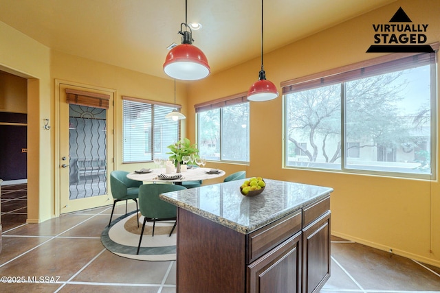 kitchen featuring dark tile patterned flooring, light stone countertops, dark brown cabinetry, and hanging light fixtures