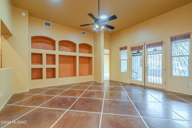 unfurnished room featuring tile patterned floors, built in shelves, ceiling fan, and french doors