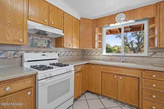 kitchen featuring light tile patterned floors, backsplash, white gas stove, and sink