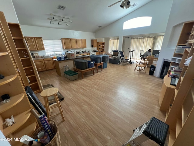 living room with light wood-type flooring, track lighting, high vaulted ceiling, and ceiling fan