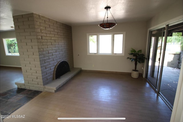 unfurnished living room with a textured ceiling and a brick fireplace