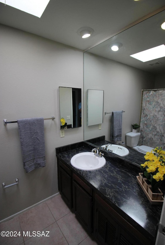 bathroom featuring toilet, vanity, a skylight, and tile patterned floors