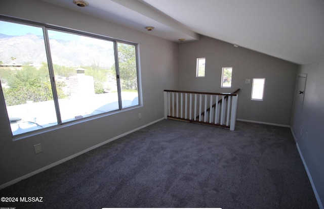 spare room featuring dark carpet and lofted ceiling