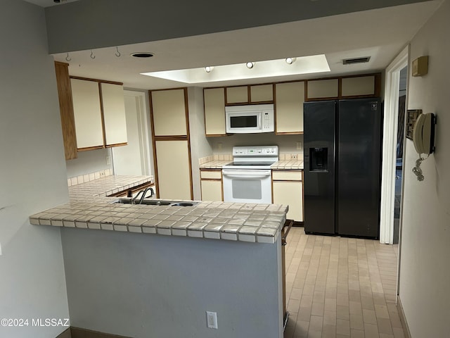 kitchen featuring tile counters, sink, white appliances, and kitchen peninsula