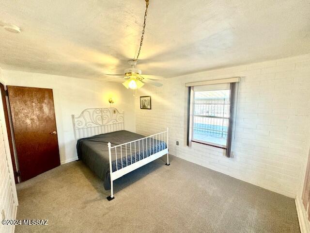 carpeted bedroom featuring ceiling fan and brick wall