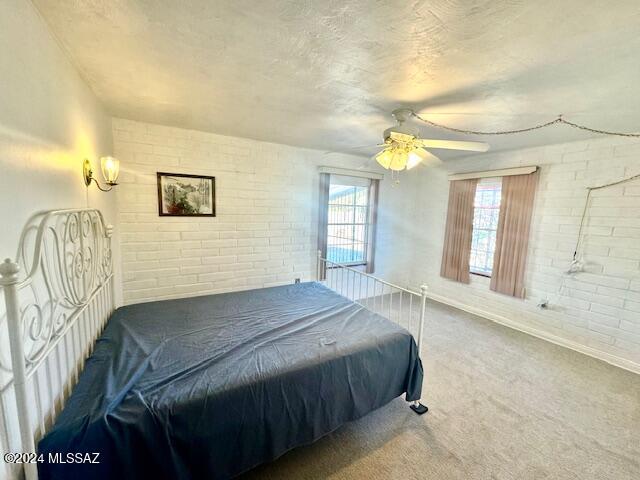 bedroom featuring carpet, brick wall, multiple windows, and ceiling fan