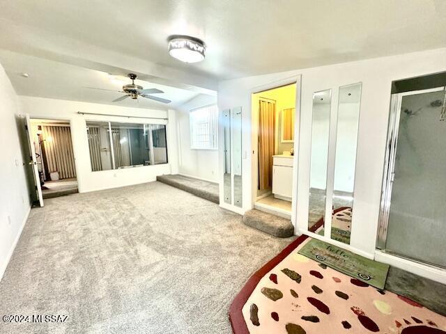 bedroom featuring ceiling fan, vaulted ceiling, carpet floors, and ensuite bath