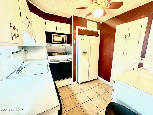 kitchen with white cabinetry, sink, a textured ceiling, white appliances, and light tile patterned flooring