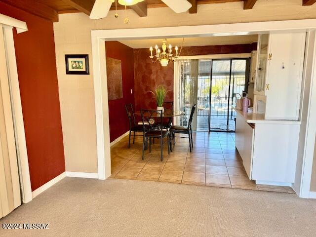 tiled dining space with beam ceiling and ceiling fan with notable chandelier