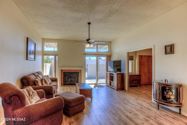 living room with ceiling fan, plenty of natural light, a textured ceiling, and light wood-type flooring