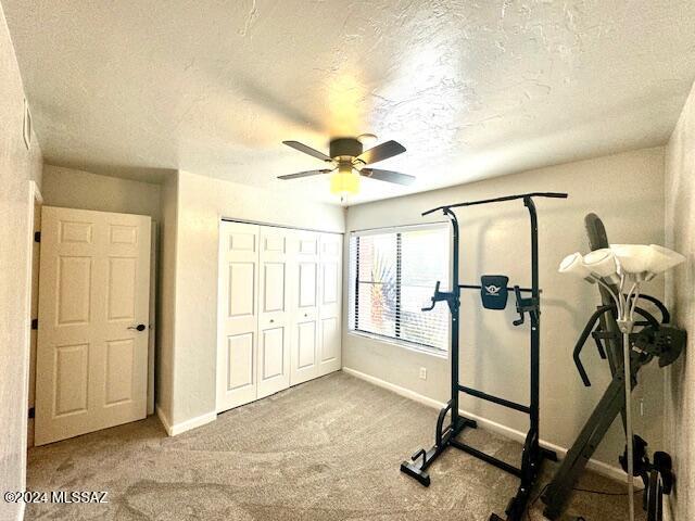 workout area featuring carpet flooring, a textured ceiling, and ceiling fan