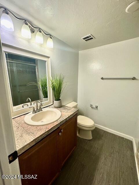 bathroom featuring hardwood / wood-style floors, vanity, a textured ceiling, and toilet