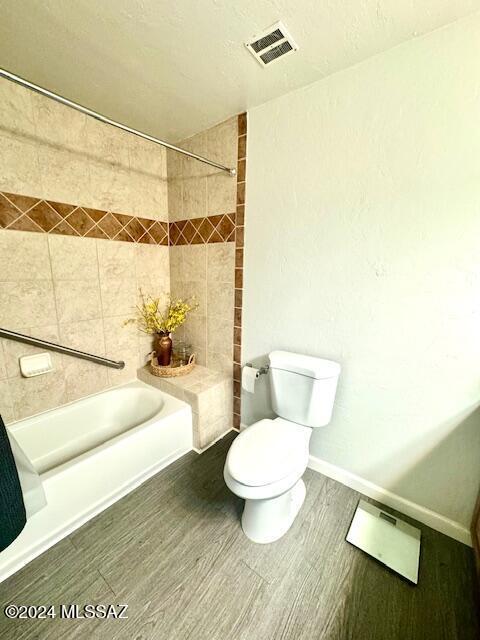 bathroom with shower / bathtub combination with curtain, wood-type flooring, and toilet