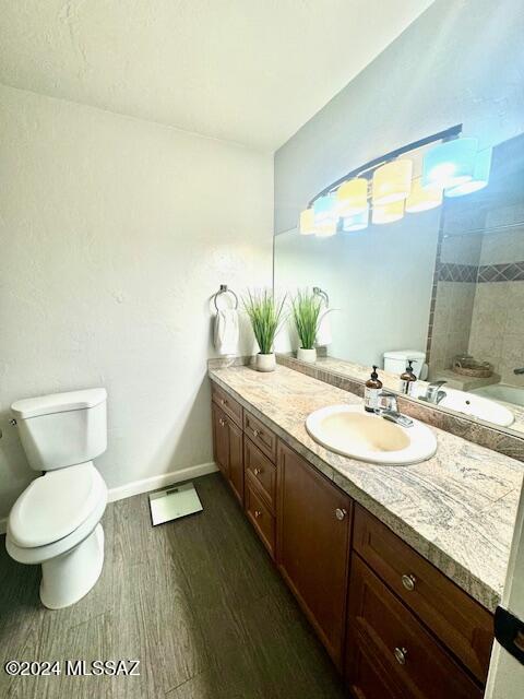 full bathroom featuring hardwood / wood-style floors, vanity, shower / bathtub combination, and toilet