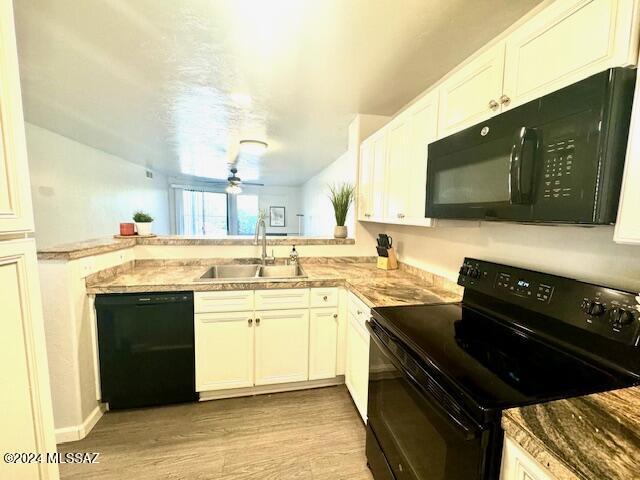 kitchen featuring ceiling fan, sink, light hardwood / wood-style floors, white cabinets, and black appliances