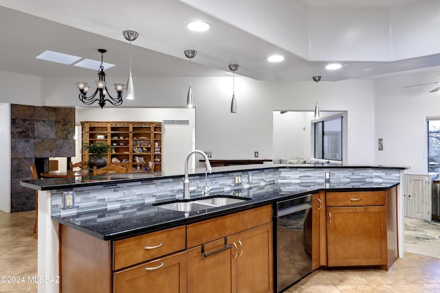 kitchen with pendant lighting, decorative backsplash, brown cabinetry, a sink, and dark stone countertops