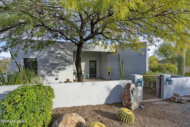 view of front facade featuring a fenced front yard, a gate, and stucco siding