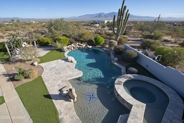 view of swimming pool featuring a patio area, a pool with connected hot tub, and a mountain view