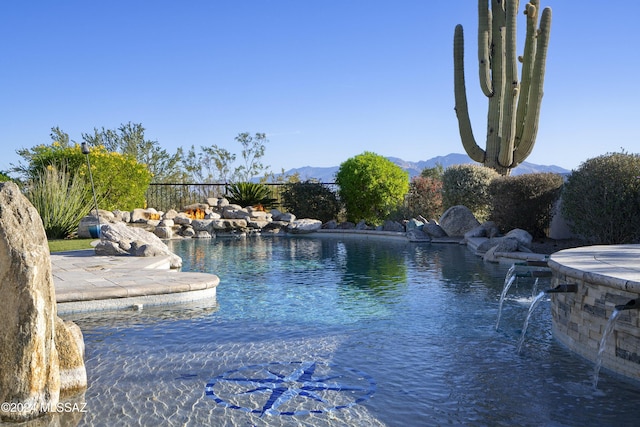 view of swimming pool with fence and a mountain view