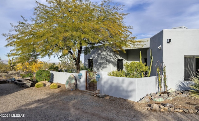 view of property exterior featuring a fenced front yard, a gate, and stucco siding