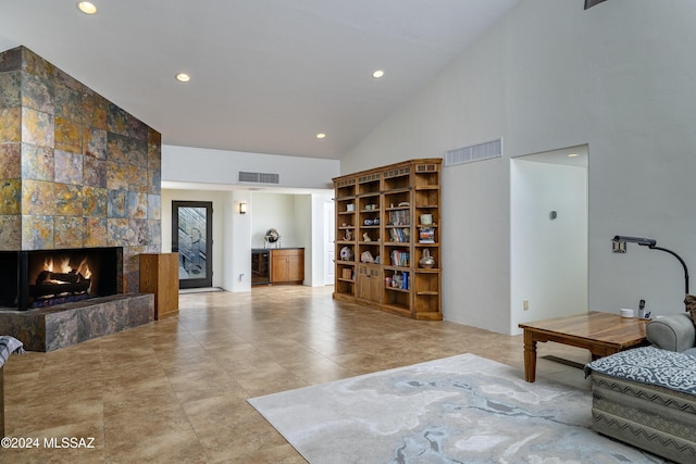 living area with high vaulted ceiling, beverage cooler, visible vents, and a tiled fireplace