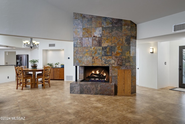 living room featuring a large fireplace, visible vents, and a notable chandelier