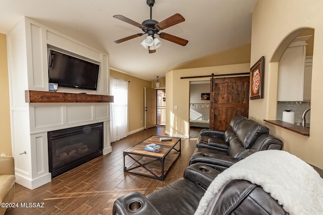 living room featuring a barn door, dark wood-type flooring, ceiling fan, and lofted ceiling