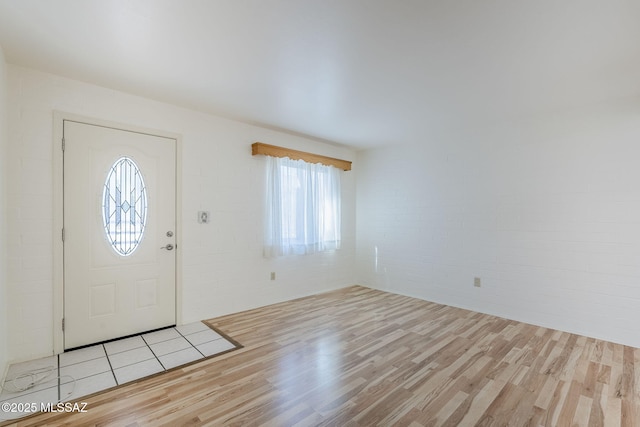 foyer with wood finished floors and brick wall