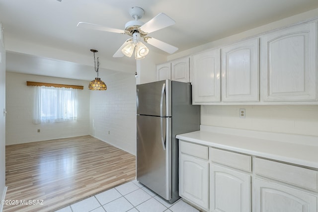 kitchen featuring decorative light fixtures, light countertops, freestanding refrigerator, white cabinetry, and a ceiling fan