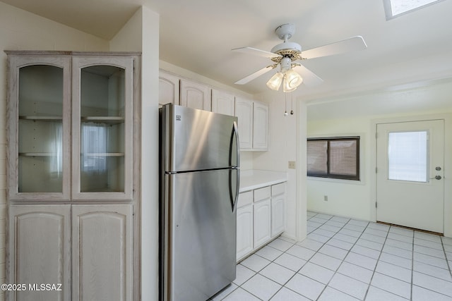 kitchen featuring freestanding refrigerator, light countertops, light tile patterned floors, ceiling fan, and vaulted ceiling