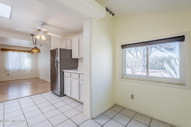 kitchen featuring a skylight, white cabinetry, sink, backsplash, and appliances with stainless steel finishes