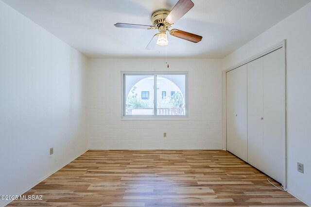 unfurnished bedroom featuring ceiling fan, light wood-type flooring, and two closets