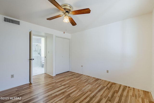 empty room with visible vents, ceiling fan, and light wood finished floors