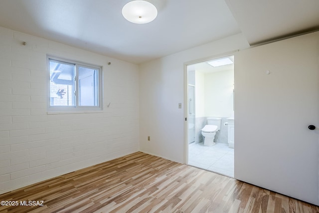 unfurnished bedroom featuring connected bathroom and wood finished floors
