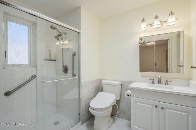 bathroom featuring wainscoting, a stall shower, vanity, and toilet