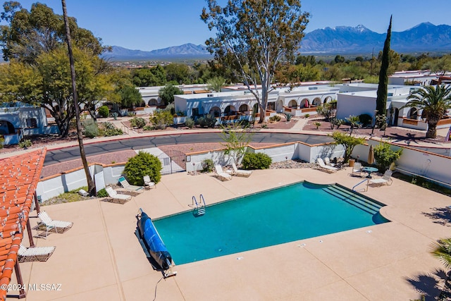 pool with a patio, fence, and a mountain view