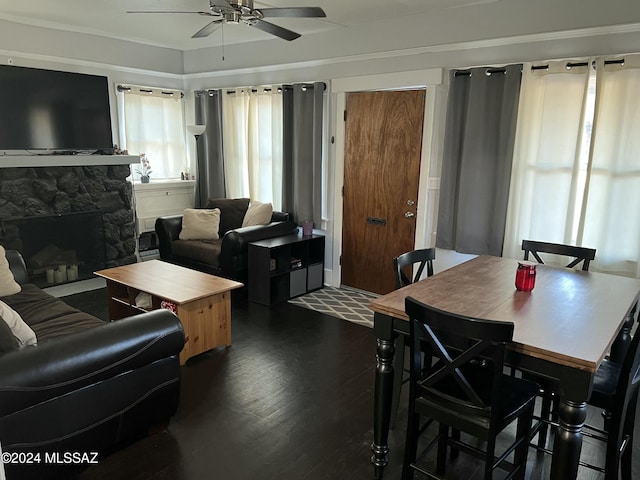 living room with dark hardwood / wood-style floors, ceiling fan, crown molding, and a fireplace