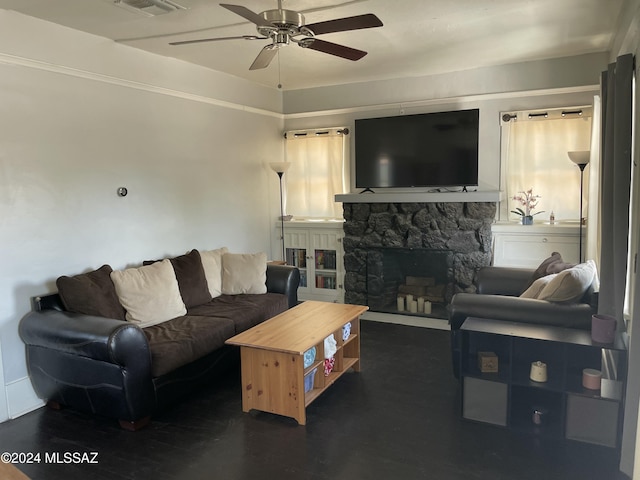 living room with dark hardwood / wood-style floors, a stone fireplace, and ceiling fan