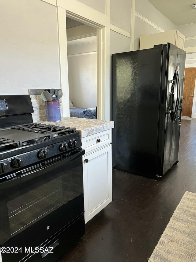 kitchen featuring dark hardwood / wood-style floors, white cabinetry, and black appliances