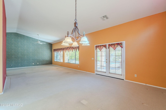 carpeted empty room with french doors, ceiling fan with notable chandelier, a healthy amount of sunlight, and lofted ceiling