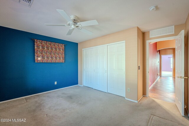 unfurnished bedroom with light carpet, a closet, and ceiling fan