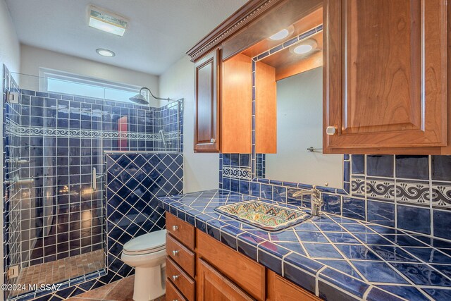 bathroom featuring tiled shower, tile patterned floors, vanity, and toilet