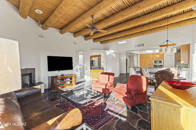 living room featuring a stone fireplace, ceiling fan, beamed ceiling, and wood ceiling