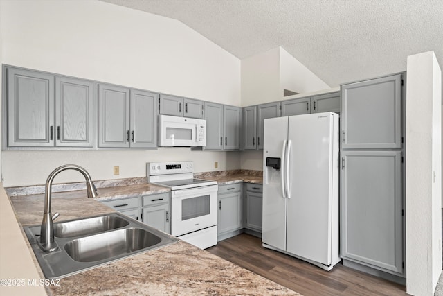 kitchen featuring dark hardwood / wood-style floors, white appliances, lofted ceiling, a textured ceiling, and sink