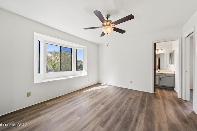 unfurnished bedroom with ceiling fan, dark wood-type flooring, and ensuite bath