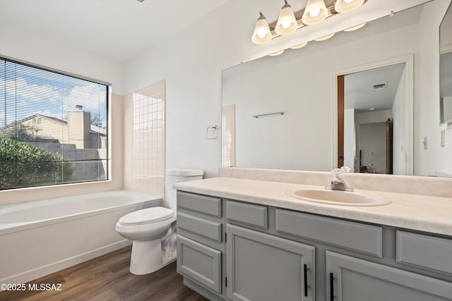 bathroom featuring hardwood / wood-style flooring, a washtub, toilet, and vanity