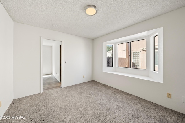 carpeted empty room featuring a textured ceiling