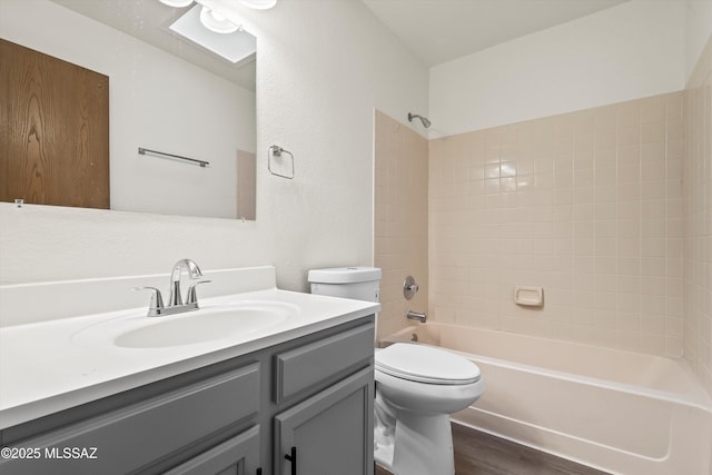 full bathroom with toilet, tiled shower / bath, hardwood / wood-style flooring, and vanity