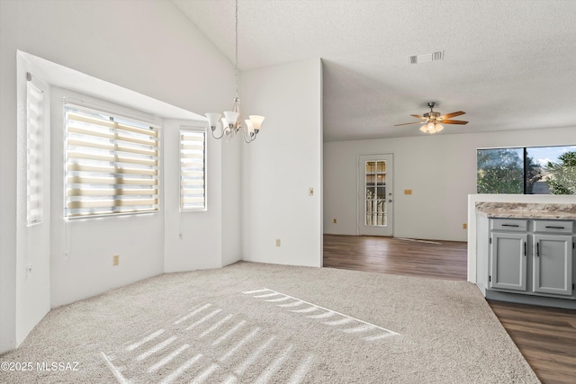 unfurnished living room featuring ceiling fan with notable chandelier and a textured ceiling