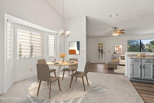 dining space with dark hardwood / wood-style flooring, ceiling fan with notable chandelier, and a textured ceiling